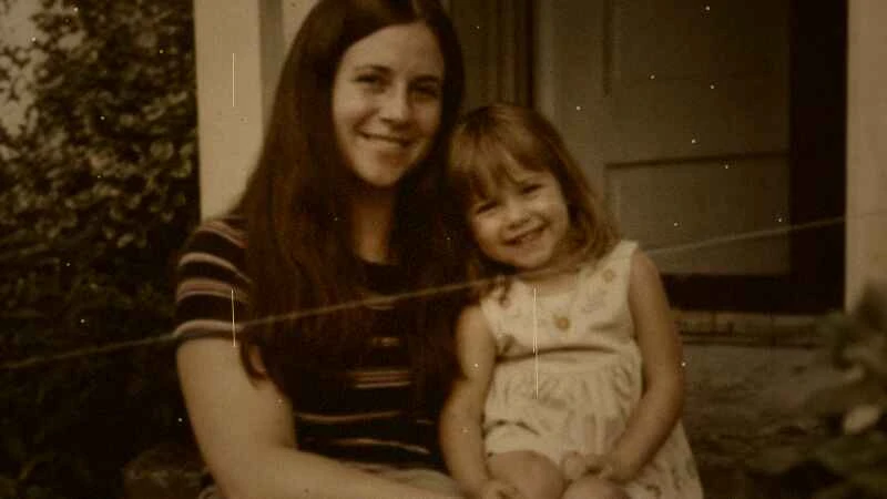 Low-resolution family photo of a mother and her young daughter smiling on a porch